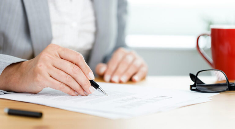 Close-up shot of businesswoman filling out insurance policy in h